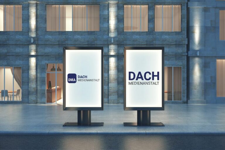 Zwei beleuchtete City-Light-Poster vor einer Altbaufassade am Abend