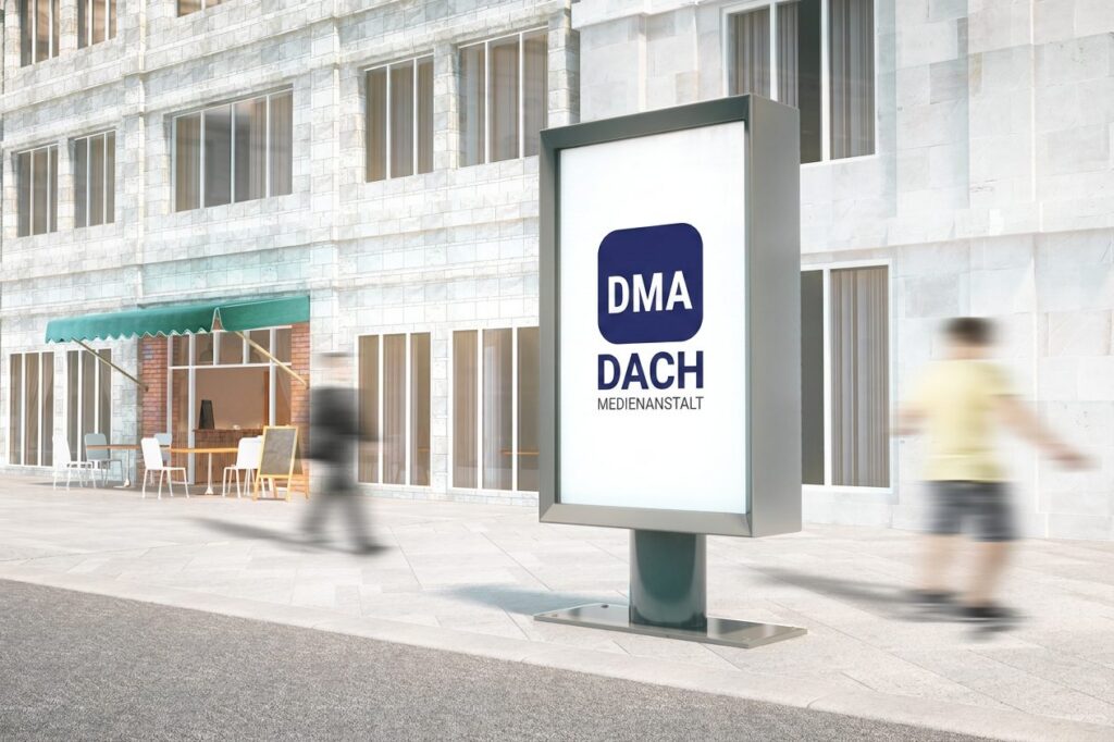 Beleuchtete City-Light-Stele auf einem belebten Gehweg, Passanten gehen vorbei