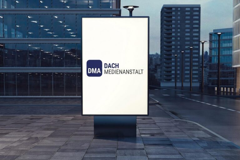 Beleuchtetes GroÃŸflÃ¤chenplakat der DACH Medienanstalt an einer HauptstraÃŸe in der AbenddÃ¤mmerung